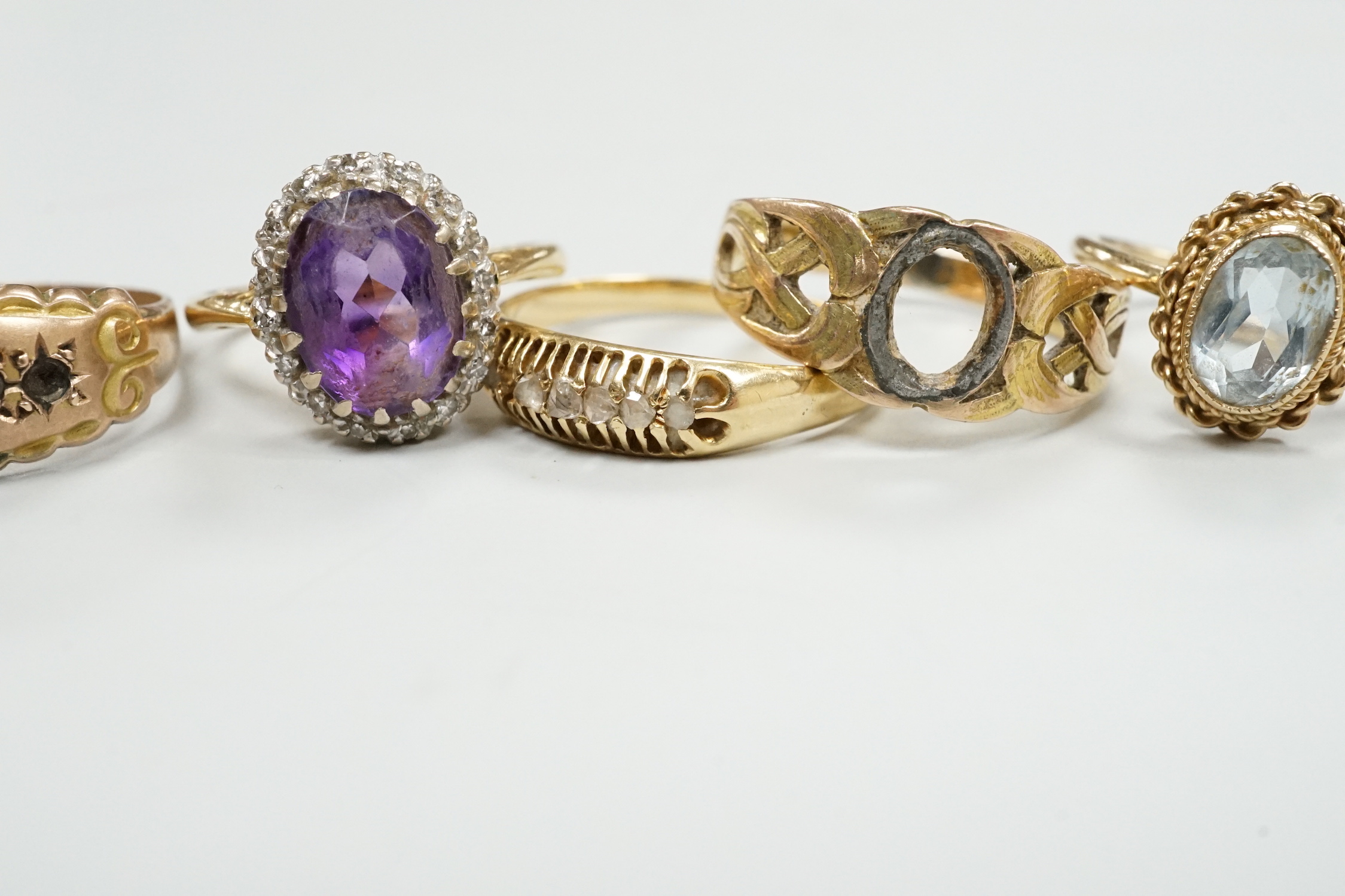 An 18ct, amethyst and diamond set oval cluster ring, size K and four other rings including gem set.